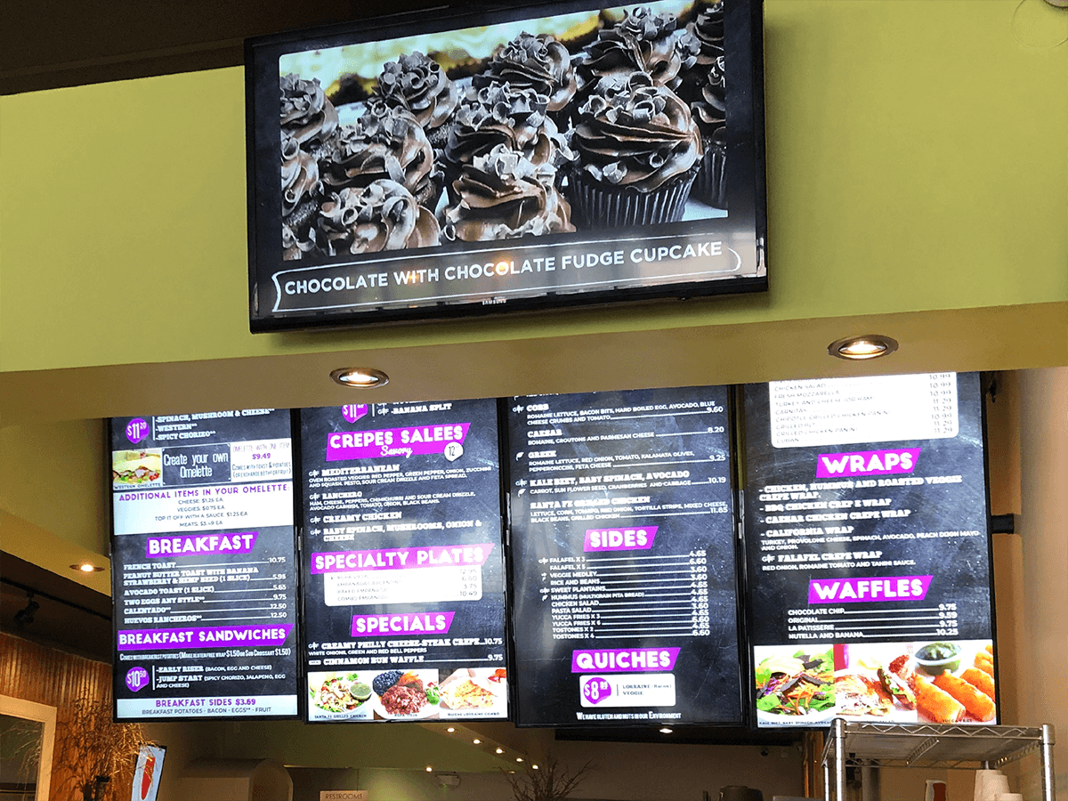 Digital menu boards above a café counter